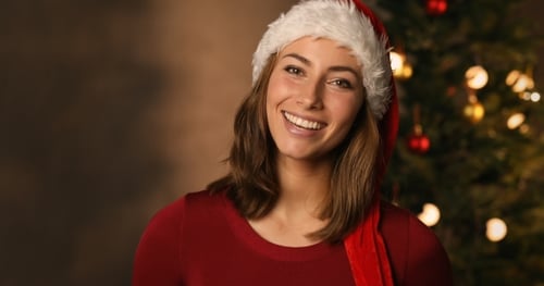 Smiling Woman in Santa Hat with Christmas Tree
