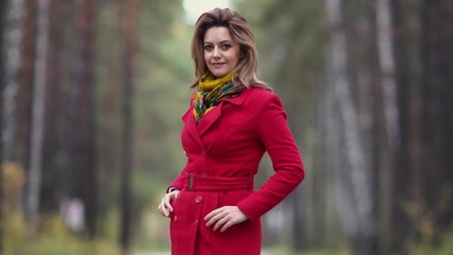 Portrait of a Young Woman in an Autumn Park. Beautiful Girl in Red Coat Posing and Smiling at the