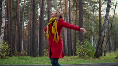 Young Woman Walking in Autumn Forest. Girl Enjoys a Warm Autumn Day. the Girl in the Red Coat and