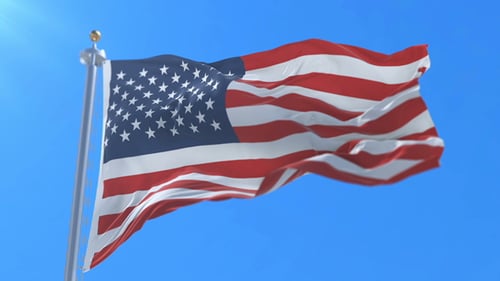 Waving American Flag on Flagpole against Bright Blue Sky