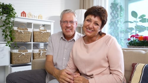 Happy Couple Smiling and Waving in Living Room