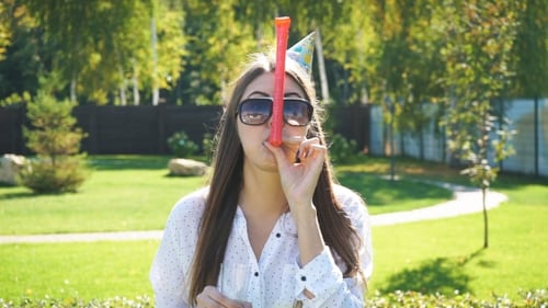 Woman Celebrates Birthday with Noisemaker and Drink