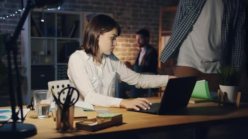 Exhausted Girl Working with Laptop When Manager Bringing More Papers at Night