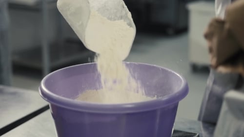 Adding Flour to Purple Bowl in Commercial Kitchen