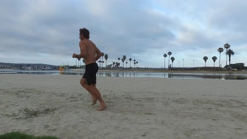 Tracking shot of a man jogging on the bay and beach