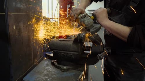 Closeup of worker using a grinder cuts metal in a workshop