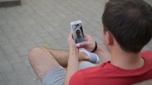 Man Video Chatting With Phone on Urban Bench