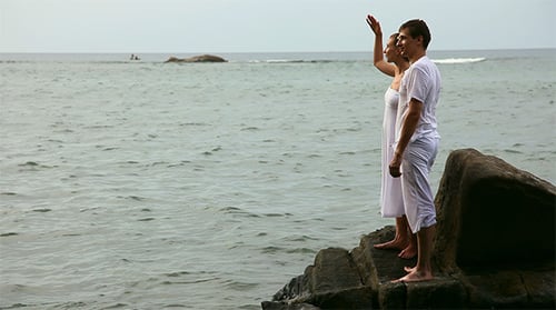 Couple Standing on Rocks Gazing at the Ocean