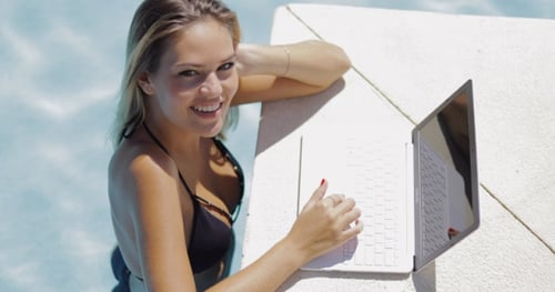Smiling Woman Relaxing in Pool with Laptop