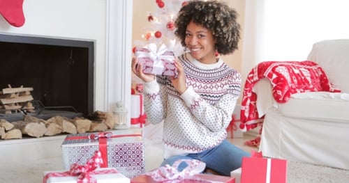 Woman Holding Christmas Present by a Fireplace