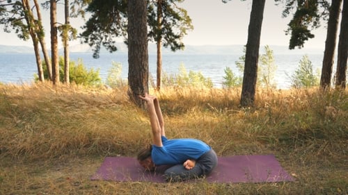 Young Man Doing Yoga in the Woods By the River