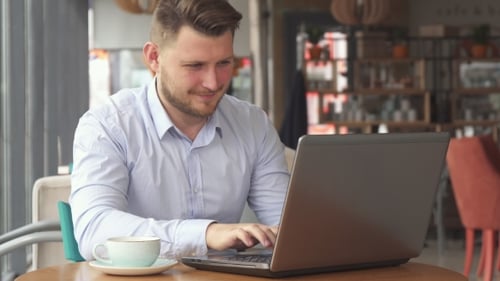 Businessman Works on Laptop at the Cafe