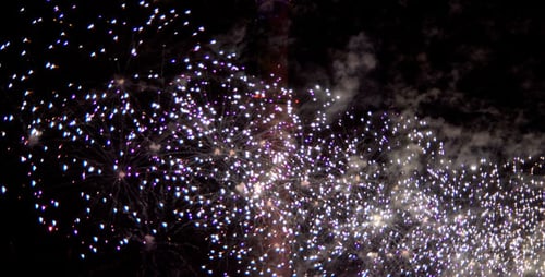 Colorful Fireworks Burst Behind Illuminated Tower at Night