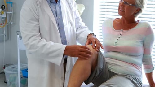 Doctor Examines Senior Woman's Knee in Office