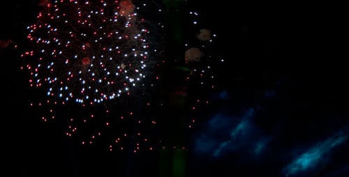 Spectacular Fireworks Exploding Around a Green Tower at Night