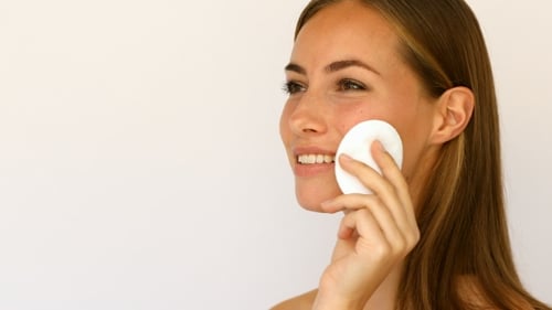 Woman Applies Beauty Product with Cotton Pad
