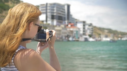 Jeune fille fait photo près de la mer bleue assise sur une montagne