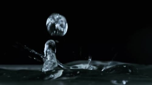 In Zeitlupen-Makroaufnahme fallen viele Wassertropfen auf die Wasseroberfläche