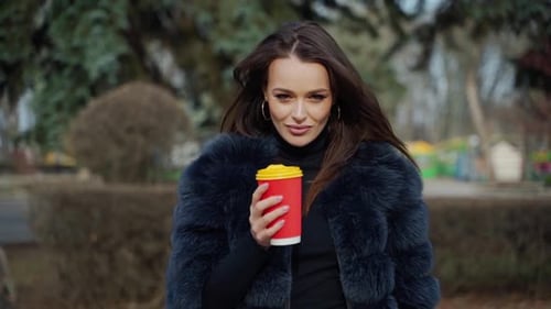 Stylish Woman Posing with Coffee in Park