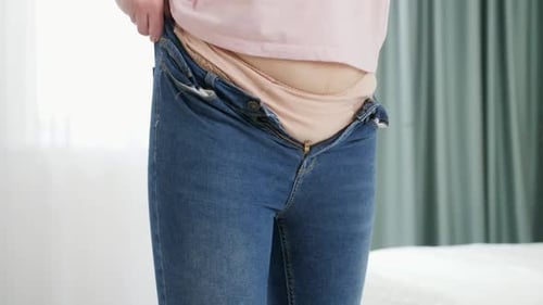 Woman Putting on Jeans in Bedroom Mid Shot
