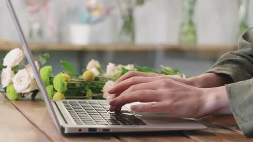 Florist Typing On Laptop At Flower Shop
