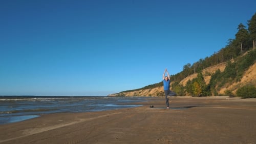 Strong Man Practicing Difficult Yoga Pose on the Beach