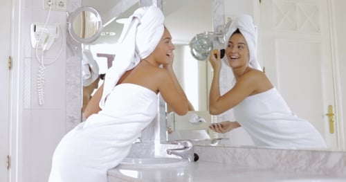 Woman Applying Makeup in Brightly Lit Bathroom