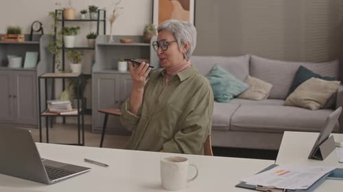 Woman Using Voice Command on Phone in Home Office