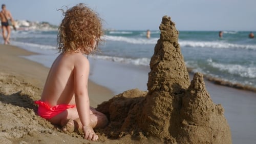 Little Girl Building Sand Castle on the Beach