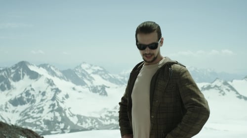 Young Bearded Man Breathing Deeply at Snowy Mountains with Scenic View