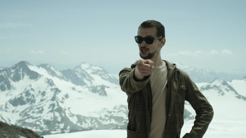 Young Bearded Man Points at Camera at Snowy Mountains with Scenic View