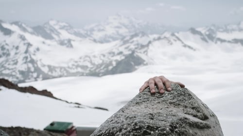 Young Guy Climber Ascents Rock at Snowy Mountain Scenic View on Sunny Day