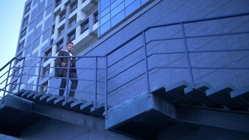 Junger stilvoller Geschäftsmann geht die Treppe hinauf in Richtung Bürogebäude