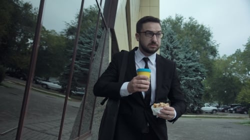 Young Adult Man Eating Lunch While on Phone