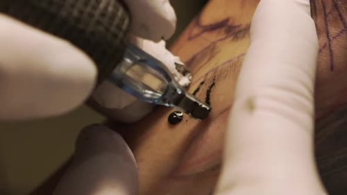 Crop master making tattoo on skin of client