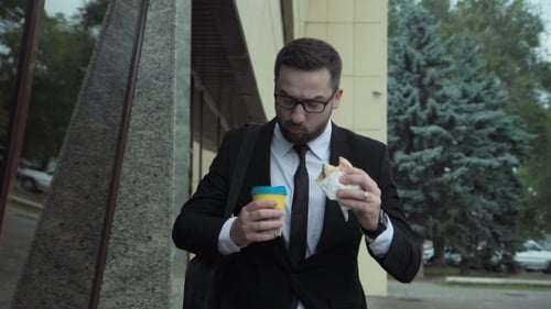 Man in Suit Eating Lunch and Talking on Phone