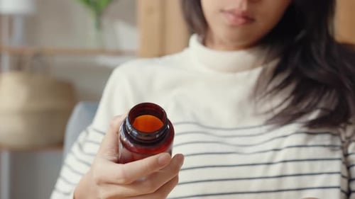 Woman Pours Pills from Bottle Into Hand