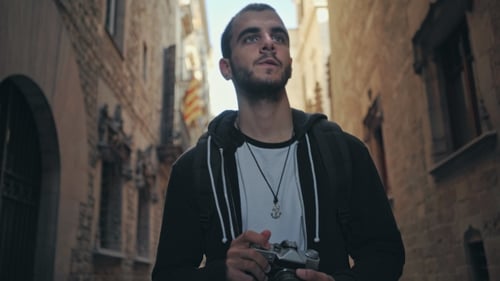 Young Man Walks with Camera in Old Town