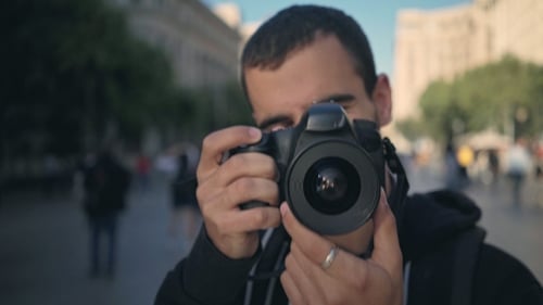 Young Man Walks with Camera in Old Town
