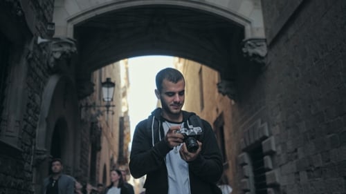 Young Man Walks with Camera in Old Town
