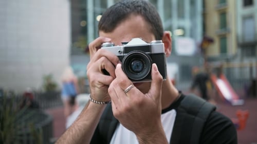 Young Man Walks with Camera in Old Town