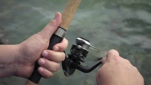 Man Reeling a Fishing Rod on River