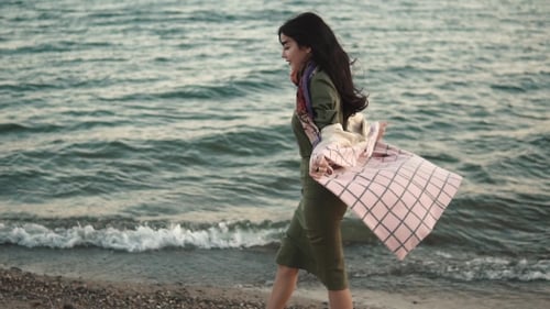 Young Woman in Autumn Coat Walking Along the Coast at Sunset.