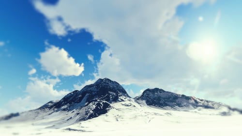 Flying Over Snowy Mountains with Blue Sky and Dynamic Clouds