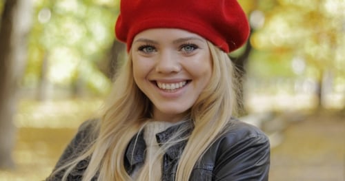 Stylish Woman Smiling in Autumnal Park Setting