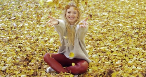 Happy Woman Playing with Autumn Leaves
