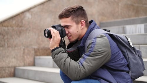 Young Man Crouching Taking a Photo With Camera
