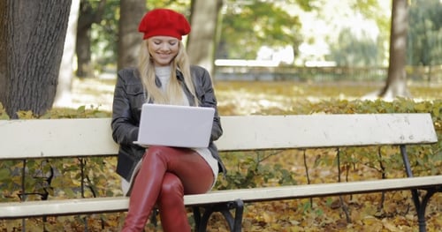 Smiling Woman Using Laptop in Park