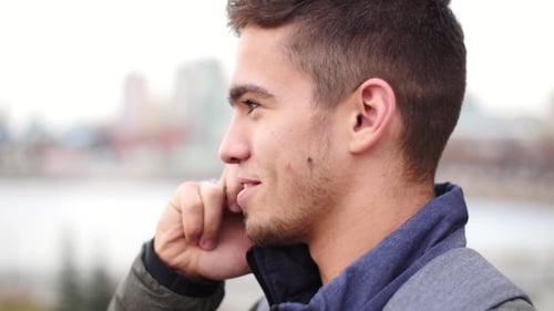 Young Stylish Man Talks on the Phone and Smiles in the City