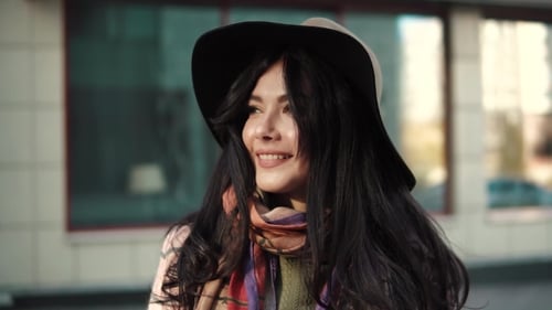 Smiling Woman in Hat and Scarf Adjusting Hat